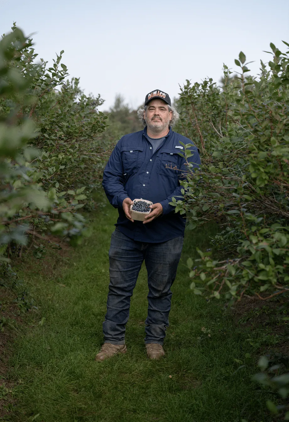 Producteur des Jardins d'Abbotsford tenant des bleuets dans son champ