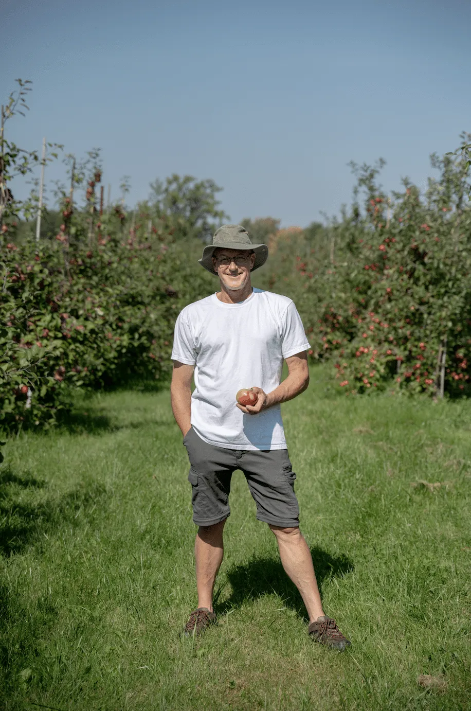 Producteur des Vergers François Juneau tenant une pomme dans son verger